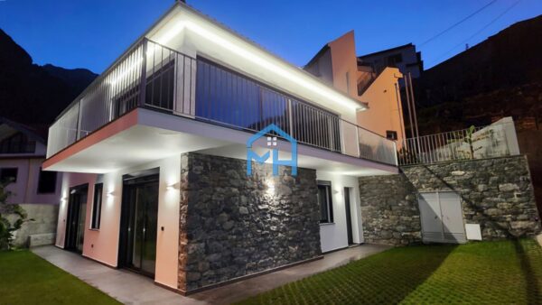 Exterior of house with light shining softly against stone walls